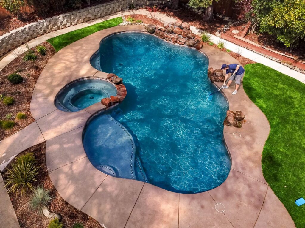 Man cleaning pool in backyard.